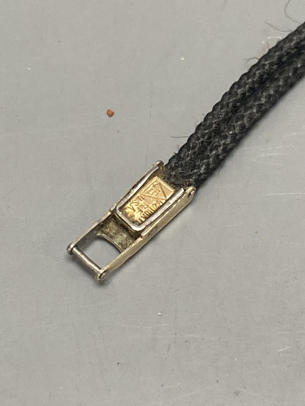 A ladys 14k Omega manual wind wrist watch, on twin strand fabric strap, case diameter 13mm ex. crown, gross 7 grams.
